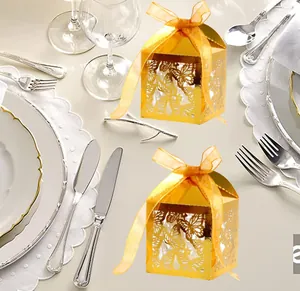 Detail of laser-cut butterfly wedding favor boxes in gold foil with orange ribbons
