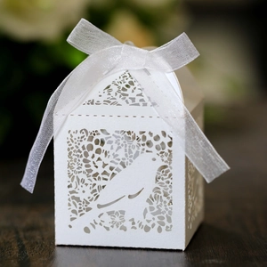 Detail of laser-cut white favor box with bird pattern and white organza ribbon bow