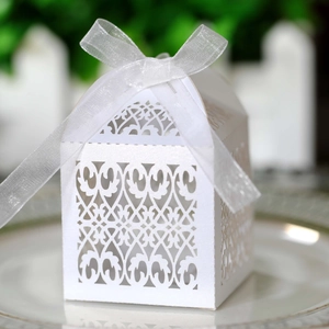 Close-up of white laser-cut hollow candy box with ribbon bow for wedding gifts