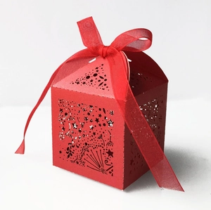 Macro view of red laser-cut wedding candy box with hollow star patterns and red ribbon bow
