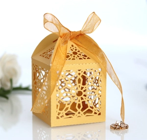 Elegant gold hollow laser-cut wedding favor box with a delicate satin ribbon bow