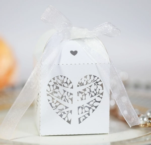 Detailed laser-cut white wedding favor box with heart-shaped leaf patterns and ribbon