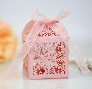 Close-up of laser-cut snowflake patterns and ribbon on this pink wedding favor box