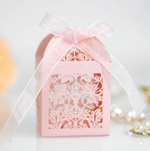 Pink laser-cut wedding favor box with elegant floral patterns and a white silk ribbon bow