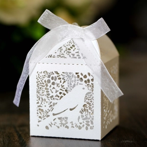 Detail of laser-cut paper candy box featuring white bird design and organza ribbon