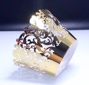 Macro shot of laser-cut lace cupcake wrappers in metallic gold with vine patterns