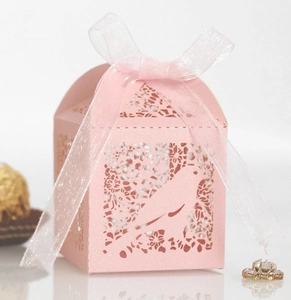 Pink laser-cut candy box with bird and flower patterns and a white satin ribbon