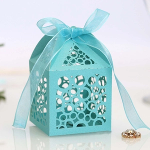 Close-up of laser-cut light blue wedding favor box with pearl finish and chiffon ribbon