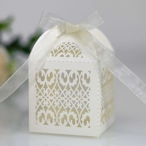 Detail of laser-cut white wedding favor box with intricate patterns and silk ribbon