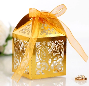Detailed laser-cut gold candy box with champagne glass motifs and yellow silk ribbon