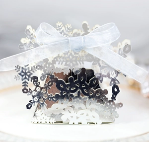 Macro view of silver laser-cut snowflake candy box with a light blue ribbon bow