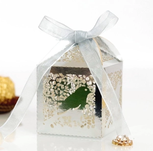 Macro shot of silver pearl paper favor box with laser-cut bird pattern and blue ribbon