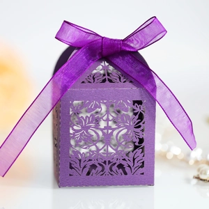 Macro shot of purple laser-cut candy box with floral pattern and silk ribbon bow