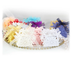 Laser-cut snowflake candy boxes with ribbon bows in multiple colors for festive gift packaging
