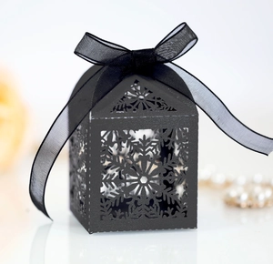 Detailed close-up of a black laser-cut snowflake gift box with an elegant ribbon bow