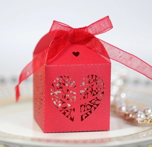 Red laser-cut wedding favor box with heart tree pattern and elegant ribbon closure