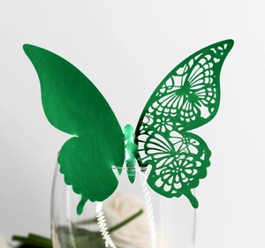 Detail of green laser-cut butterfly card clipped on a glass rim for party decor