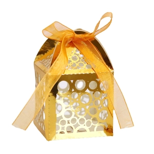 Golden laser-cut party favor box with round hollow patterns and orange organza ribbon