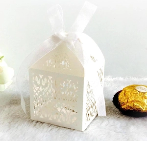 Macro detail of laser-cut house-shaped wedding favor box with white silk ribbon bow