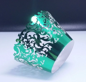 Detail of green laser-cut metallic cupcake wrapper with intricate lace floral patterns
