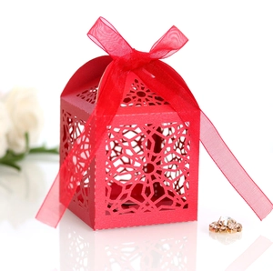 Detailed laser-cut red lace candy box with elegant ribbon bow for wedding favors