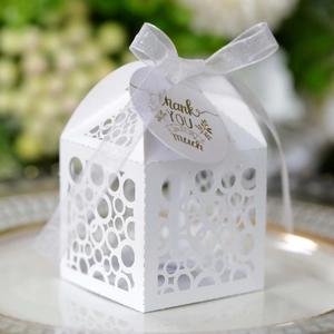 Detail of white hollow-out gift box with ribbon and gold Thank You hanging tag