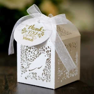 Detail of laser-cut wedding favor box with bird lace pattern and silk ribbon tie