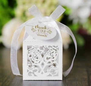 Macro detail of laser-cut wedding favor box with champagne glass pattern and thank you tag