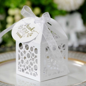 White laser-cut favor box with ribbon and gold Thank You tag on elegant dinnerware