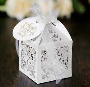Close-up of laser-cut wedding gift box with white ribbon and a gold thank you tag