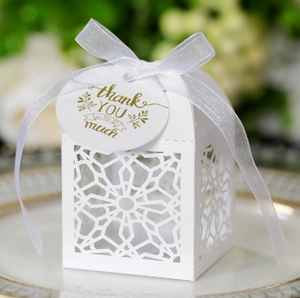Close-up of white lace laser-cut candy box with ribbon bow and a gold Thank You tag