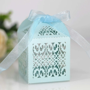 Close-up of light blue laser-cut wedding favor box with organza ribbon and floral pattern