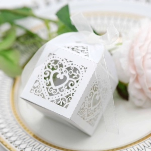 White laser-cut heart candy box with silk ribbon on elegant tray for wedding decor