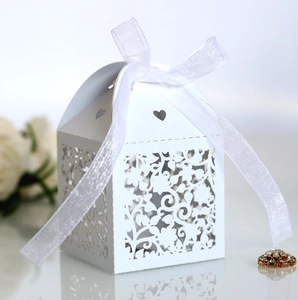 Detail of laser-cut heart pattern on white wedding favors box with elegant silk ribbon