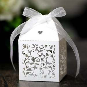 Detailed laser-cut floral pattern on white paper wedding favor box with a ribbon bow