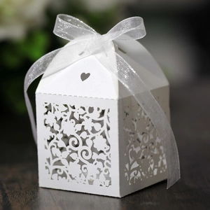Detail of laser-cut white flower candy box with heart pattern and organza ribbon