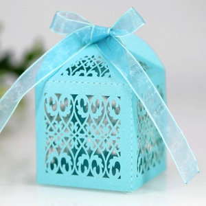 Close-up of light blue laser-cut wedding candy box with intricate floral patterns and ribbon
