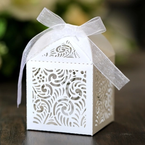 Detail of white laser-cut hollow paper candy box with ribbon for wedding party favors
