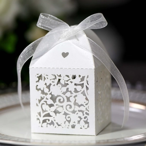Close-up of white laser-cut wedding favor box with heart design and organza ribbon bow