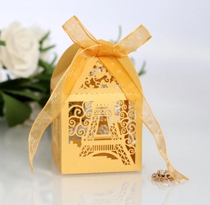 Detail view of golden Eiffel Tower laser-cut favor box with yellow organza ribbon bow
