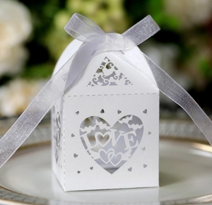 Close-up of laser-cut heart candy box with LOVE text and white satin ribbon bow