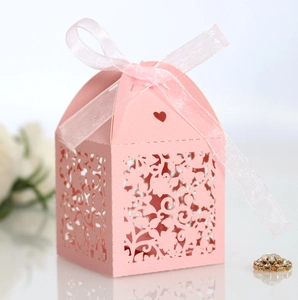 Close-up of pink laser-cut flower wedding favor box with ribbon bow on pearlescent paper