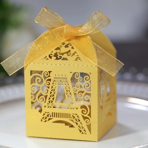 Detailed laser-cut Eiffel Tower favor box in shiny gold with silk ribbon bow decor