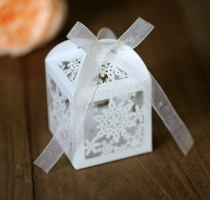 Detail of white laser-cut snowflake candy box with elegant white organza ribbon bow