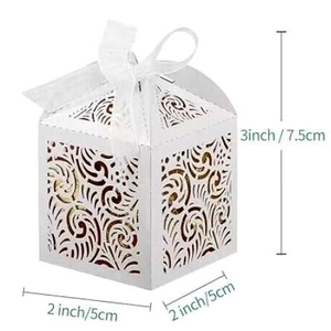 Detailed view of white laser-cut favor box with ribbon and 2x2x3 inch size dimensions
