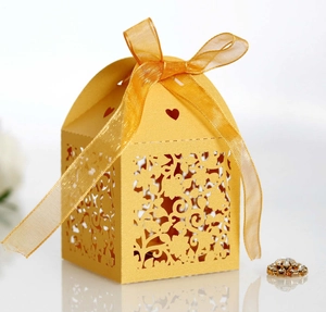 Close-up of laser-cut gold wedding favor box with intricate floral hollow patterns