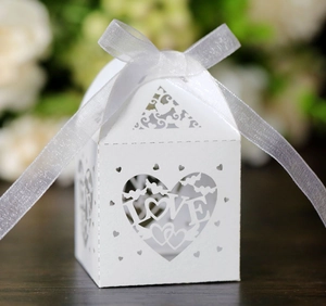 Detail of laser-cut white wedding favor box with LOVE heart motif and organza ribbon bow