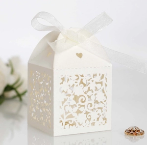 Detailed laser-cut wedding favor box with white ribbon bow and floral hollow patterns