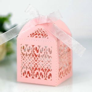 Detail of pink laser-cut gift box with intricate heart patterns and white silk ribbon