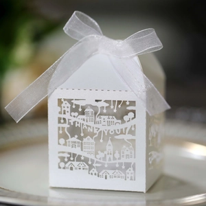 Macro detail of laser-cut white favor box with Thank You text and ribbon bow
